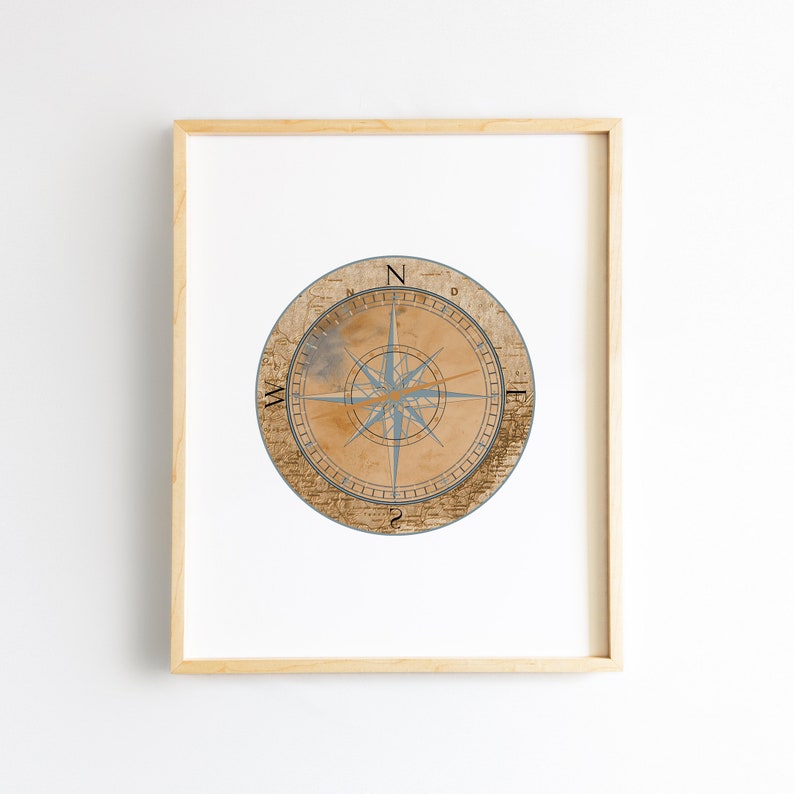 May include: A framed print of a vintage compass with a blue and gold design on a beige background. The compass has the letters N, S, E, and W around the edge.