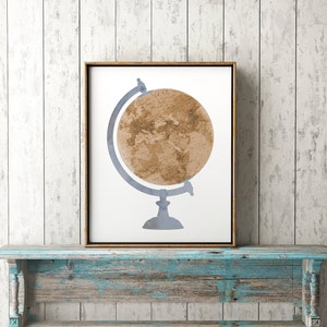 May include: A framed print of a watercolor illustration of a globe on a stand. The globe is a muted brown color with a light blue stand.