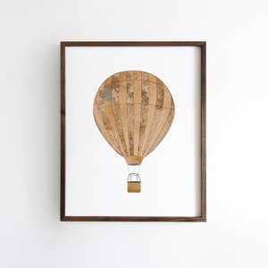 May include: A framed print of a brown and white hot air balloon with a striped pattern. The balloon is against a white background.