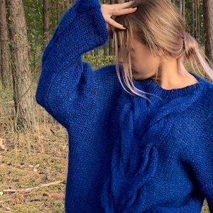 May include: A royal blue cable knit sweater with a loose fit and long sleeves.