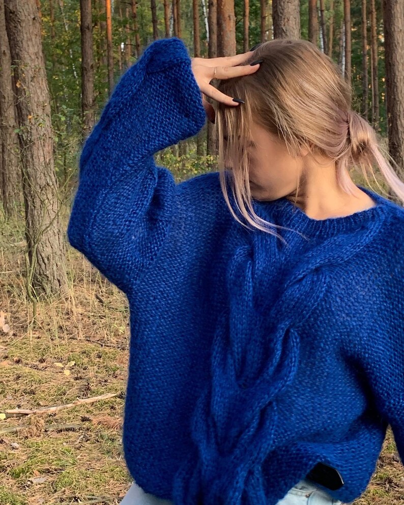 May include: A royal blue cable knit sweater with a loose fit and long sleeves.