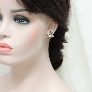 May include: A pair of gold tone earrings with a cluster of white pearls and clear rhinestones.