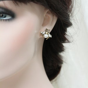 May include: Gold tone earrings with a cluster of clear and white rhinestones and a single pearl in the center.