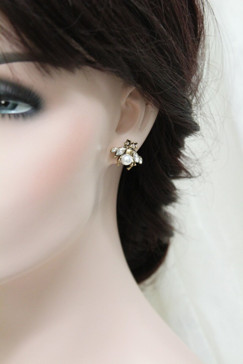 May include: Gold tone earrings with a cluster of clear and white rhinestones and a single pearl in the center.