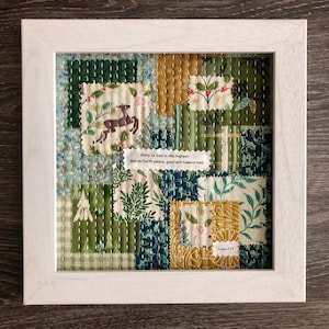 May include: A framed patchwork textile art piece with a white wooden frame. The artwork features various fabric patterns in shades of green, blue, and gold. The text "Glory to God in the highest, and on Earth peace, good will toward men" is visible.