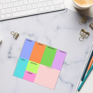 May include: A square weekly planner notepad featuring color-blocked sections for each day of the week. The layout includes blue for Monday, orange for Tuesday, green for Wednesday, purple for Thursday, teal for Friday, lime for Saturday, and pink for Sunday, with a lined section labeled Notes & To-Do.