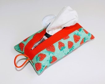 May include: A rectangular tissue holder with a strawberry pattern on a teal background. The holder has a bright orange trim and a matching loop. White tissues are visible at the top.