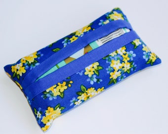 May include: A rectangular tissue holder with a blue floral pattern featuring yellow and white flowers. The holder has a solid blue band across the top. The tissue opening is visible. The item is likely handmade.
