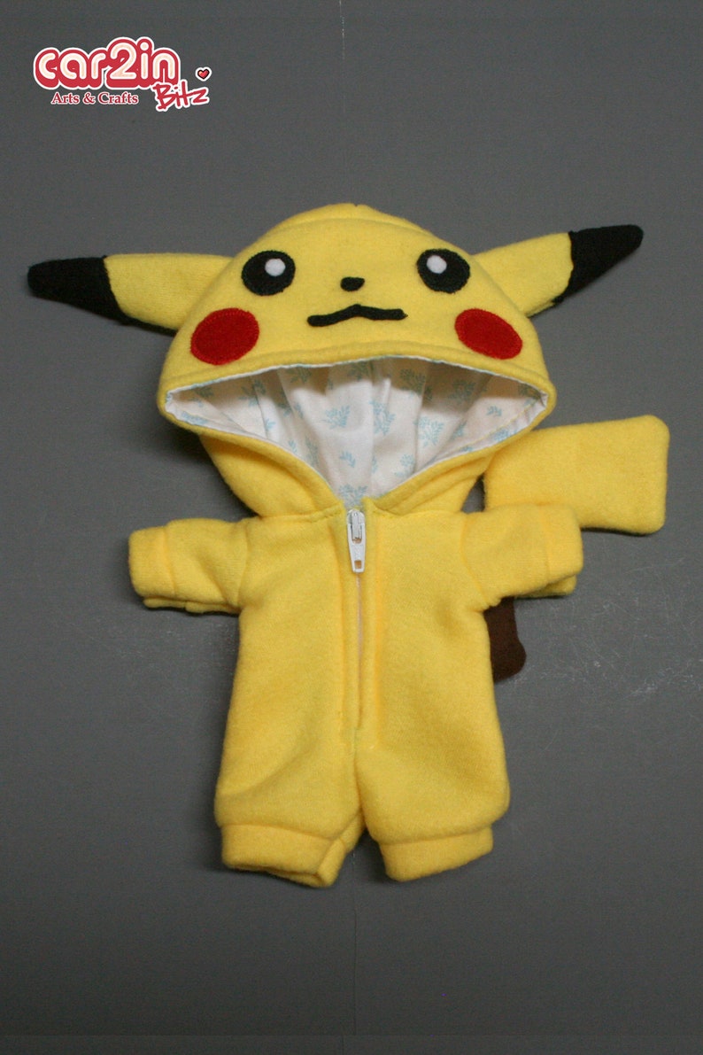 May include: Yellow Pikachu plush toy wearing a yellow hooded jumpsuit with a zipper. The hood has black ears and red cheeks. The jumpsuit has a white lining.