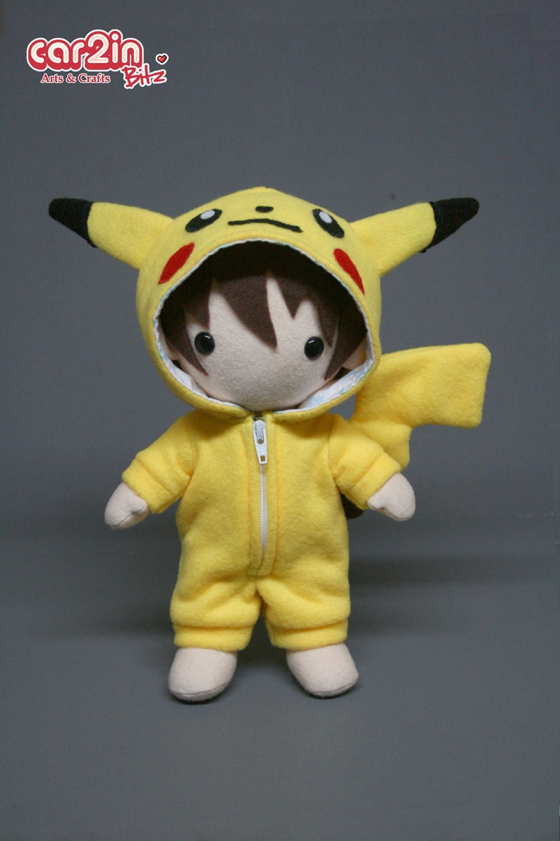 May include: A yellow plush toy wearing a Pikachu costume. The toy has brown hair, a white face, and black eyes. The costume has red cheeks and a black tail.