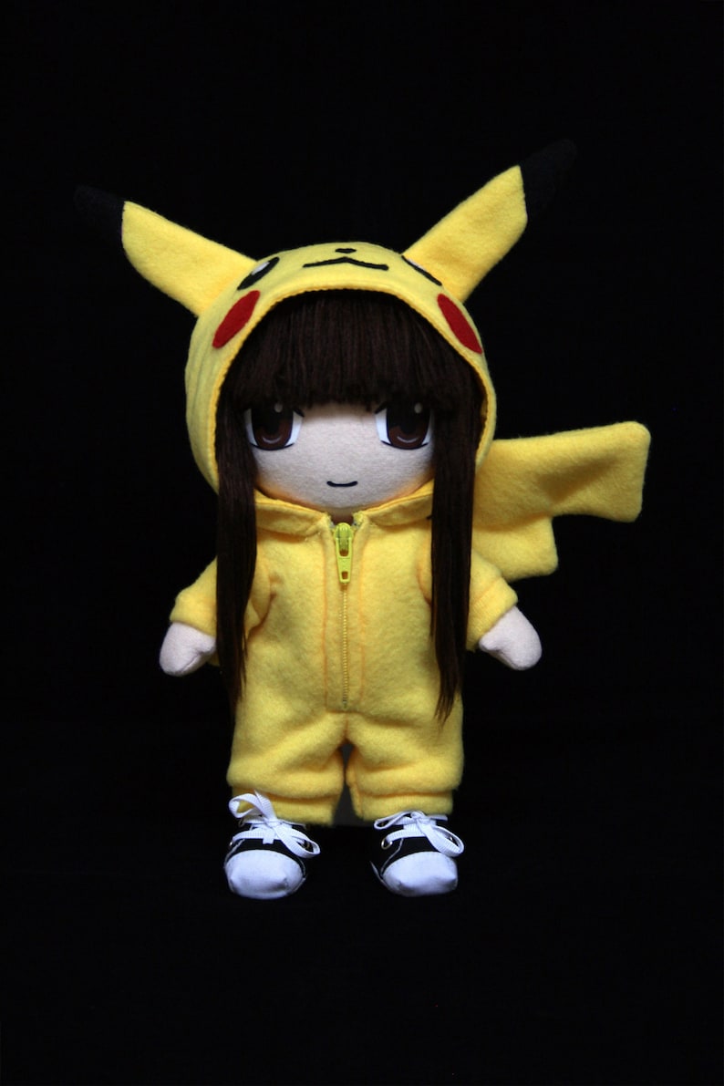 May include: A plush toy doll wearing a yellow Pikachu costume with black hair and a zipper on the front. The doll is wearing black and white sneakers.