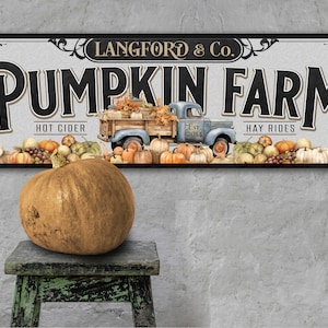 May include: A vintage-style sign for a pumpkin farm, featuring a blue truck loaded with pumpkins and fall foliage. The sign reads "Langford & Co. Pumpkin Farm" with the text "Hot Cider" and "Hay Rides" on either side of the truck.