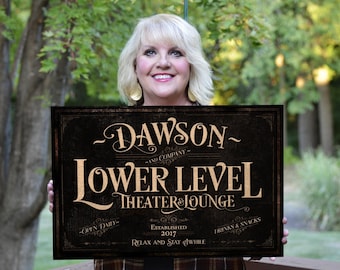 May include: A rectangular, dark brown sign with the words "DAWSON" and "LOWER LEVEL THEATER & LOUNGE" in a vintage font. The sign also includes the text "OPEN DAILY", "ESTABLISHED 2017", "RELAX AND STAY AWHILE", and "DRINKS & SNACKS".
