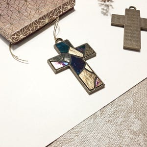 Peut inclure: Deux croix en m&eacute;tal, l'une avec un motif de vitrail dans des tons de bleu, brun et blanc, et l'autre une croix brune unie.