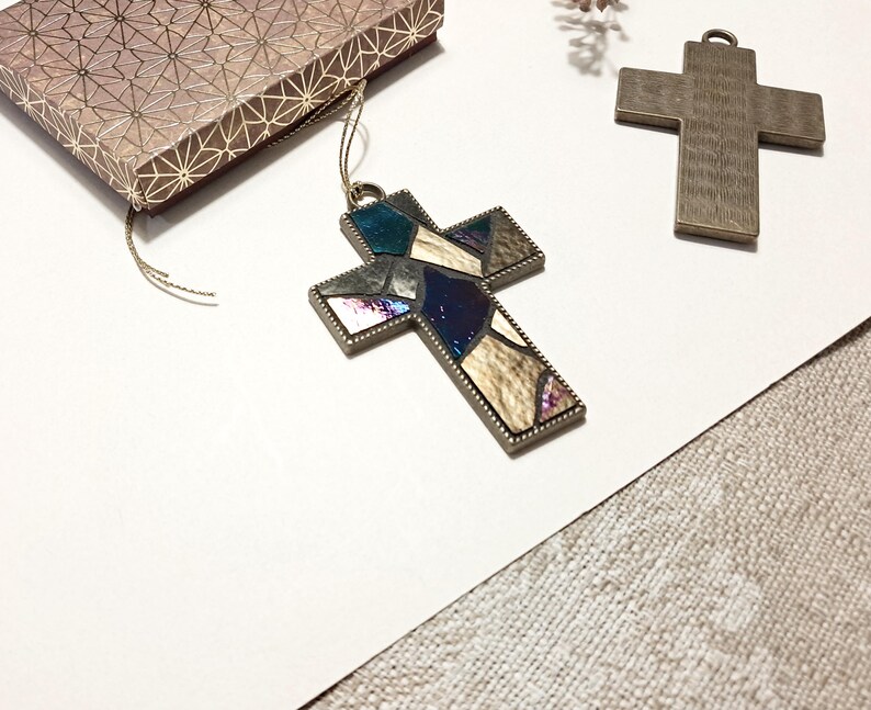 Peut inclure: Deux croix en m&eacute;tal, l'une avec un motif de vitrail dans des tons de bleu, brun et blanc, et l'autre une croix brune unie.
