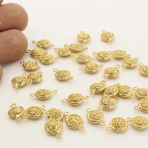 May include: A group of gold-toned metal connector charms with a filigree design. Each charm has two loops for attaching to jewelry.