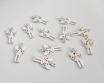 May include: A group of silver angel charms with a rhinestone in the center of each charm. The charms are scattered on a white surface.