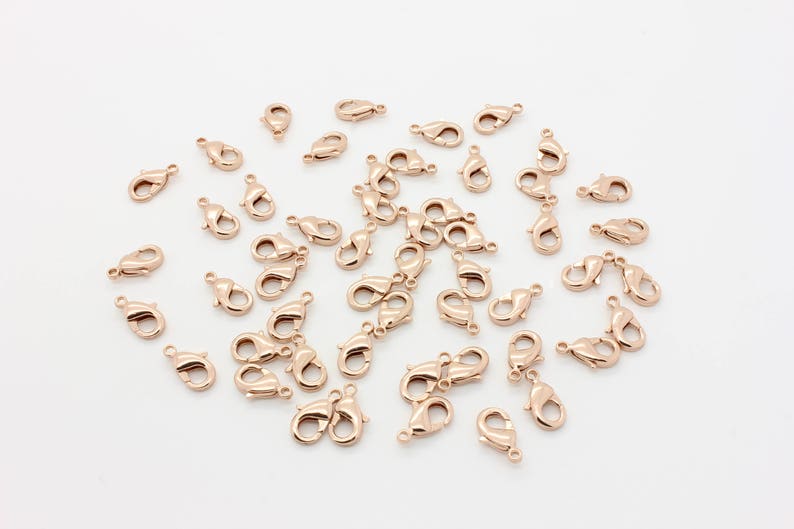 May include: A large group of rose gold lobster clasps, a type of jewelry finding used for attaching chains and cords to jewelry.