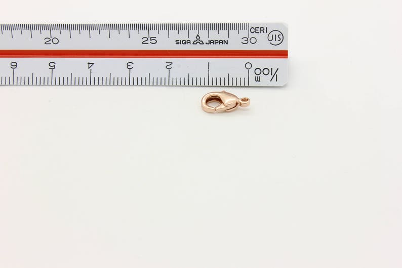 May include: A rose gold lobster clasp for jewelry making. The clasp is about 2.5 cm long.