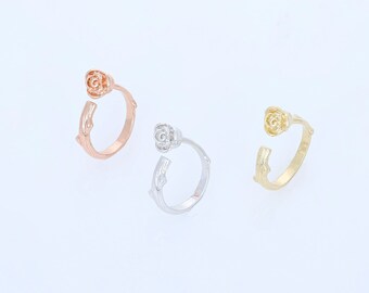 Può includere: Tre anelli a forma di rosa in diverse finiture metalliche: oro, argento e oro rosa. Ogni anello presenta un delicato motivo a rosa con stelo e foglie.
