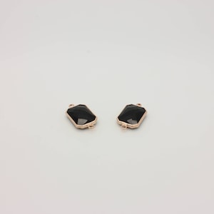 May include: Two black gemstone connectors with gold-toned metal frames. The connectors have a rectangular shape with rounded corners.