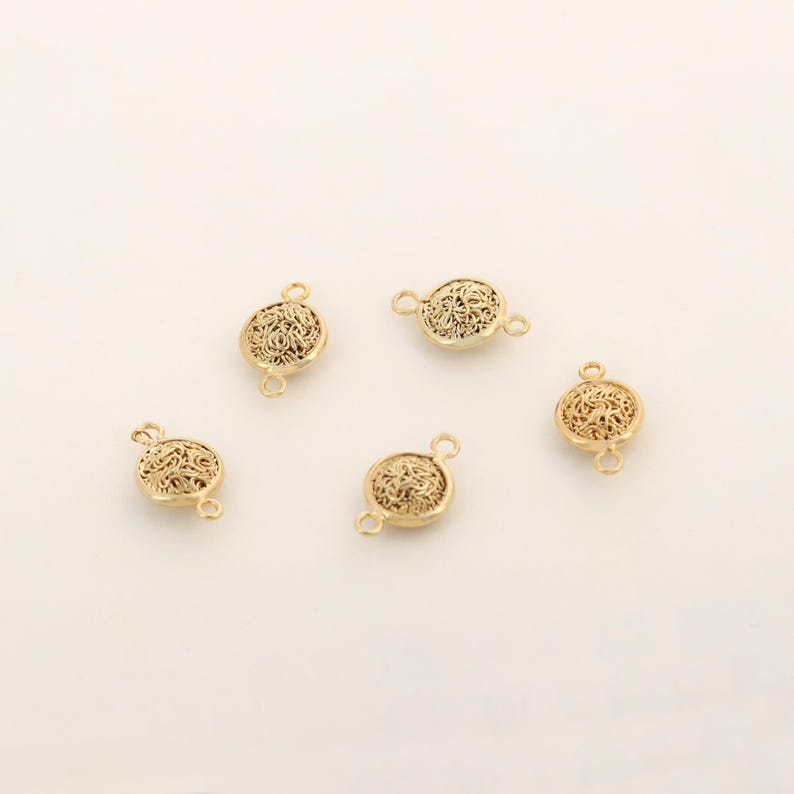 May include: Five gold-toned filigree metal connector charms with two jump rings on each charm.