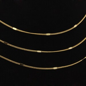 May include: Four gold chains with oval-shaped links, layered on a black background.