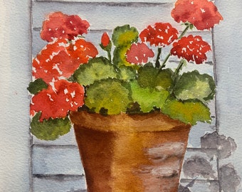 May include: A watercolor painting of a terracotta pot with red geraniums in bloom. The pot is sitting on a windowsill with white painted wooden shutters.