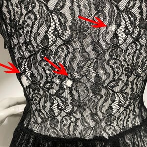K&ouml;nnte beinhalten: Nahaufnahme eines schwarzen Spitzenkleides. Das komplizierte florale Spitzenmuster ist vor einem wei&szlig;en Hintergrund sichtbar. Das Kleid hat ein figurbetontes Oberteil und einen ausgestellten Rock mit zarter, strukturierter Optik.