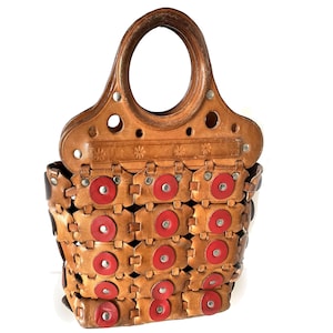 May include: A woven leather handbag with a circular wooden handle. The bag is brown with red circles and metal accents.