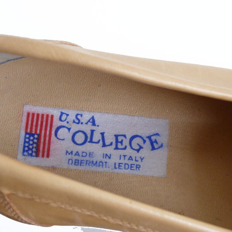 Puede incluir: Primer plano del interior de un zapato de cuero beige. Se ve una etiqueta rectangular con el texto "U.S.A. COLLEGE MADE IN ITALY OBERMAT. LEDER" y una peque&ntilde;a bandera americana.
