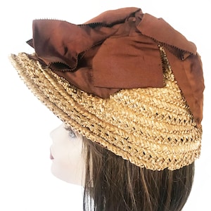 Peut inclure: Un chapeau de paille brun avec un grand nœud en satin brun. Le chapeau est tissé avec un motif délicat et a une large bordure.