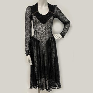 K&ouml;nnte beinhalten: Schwarzes Spitzenkleid mit langen &Auml;rmeln und V-Ausschnitt. Das Kleid hat ein figurbetontes Oberteil und einen ausgestellten Rock, der eine elegante Silhouette schafft. Die aufwendigen Spitzendetails verleihen dieser Abendgarderobe einen Hauch von Vintage-Charme.