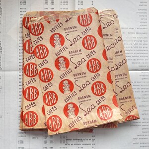May include: Vintage paper coffee bags with a repeating pattern of red circles featuring the text "ABB Caf&eacute;s" and "Koffies" in a serif font. The bags have a distressed, aged appearance.