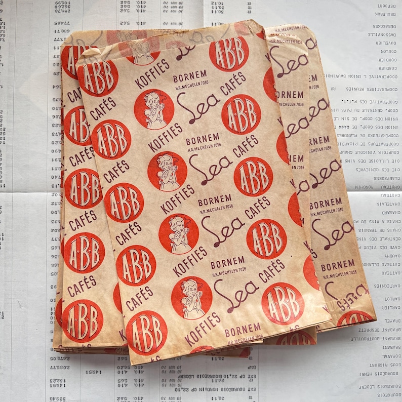 May include: Vintage paper coffee bags with a repeating pattern of red circles featuring the text "ABB Caf&eacute;s" and "Koffies" in a serif font. The bags have a distressed, aged appearance.