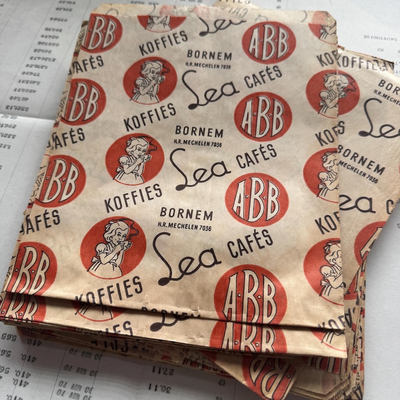 May include: Vintage coffee bags with a repeating pattern of red circles, featuring a woman drinking coffee, and the text "Koffies" and "Sea Caf&eacute;s." The bags are tan with black and red text, and the text "Bornem" is also visible.