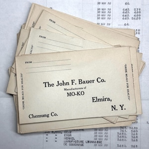 May include: A stack of vintage postcards with the text "Drink Mo-Ko for Health" and "The John F. Bauer Co. Manufacturers of Mo-Ko Elmira, N.Y. Chemung Co."