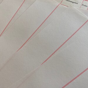 May include: Stack of white paper sheets with red lines running diagonally across the surface. The top sheet has the words "Ontvangsten" and "Folio" printed on it.
