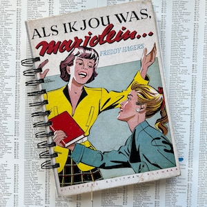 Pode incluir: Um livro ilustrado intitulado "Als ik jou was, mariclein..." de Freddy Hagers. O livro está aberto em uma página que mostra duas mulheres conversando. O livro é um caderno espiral.