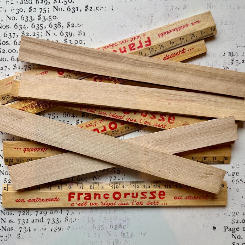 Puede incluir: Una pila de reglas de madera con texto rojo que dice "Francorusse c'est un r&eacute;gal que l'on sert... au dessert..." y "... c'est un r&eacute;gal que l'on sert..."