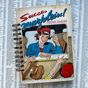 Pode incluir: Uma ilustração de estilo vintage de uma mulher com uniforme azul e chapéu vermelho acenando de uma janela de trem. O texto "Succelein!" e "FREDDY HAGERS" está impresso na capa do livro. O livro é intitulado "UITGEVERU KLUITMAN ALKMAAR".