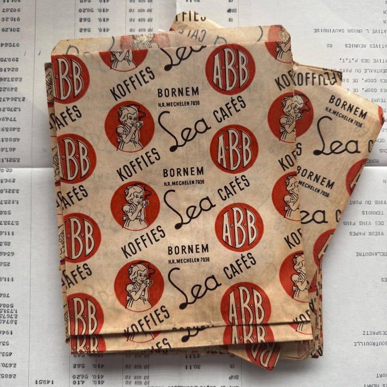 May include: Vintage paper packaging with a repeating pattern of red circles with "ABB" and "KOFFIES" text, and a drawing of a woman. The words "Sea Caf&eacute;s" and "Bornem" are also printed on the paper.