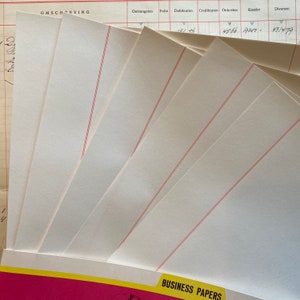 May include: A stack of blank white business papers with red lines. The papers are folded in half and are ready to be used for writing or printing.
