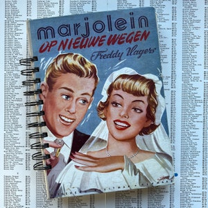 Pode incluir: Uma capa de livro vintage com fundo azul que apresenta um casal em uma cena de casamento. O título do livro é "Marjolein Op Nieuwe Wegen" de Freddy Wagers.