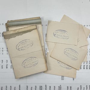 May include: A stack of vintage, cream-colored envelopes with a purple stamp that reads "G.M. TECO 30, RUE DE TOURNAI COURTRAI".