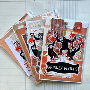 Op de afbeelding: Een verzameling vintage ephemera met apen, palmbomen en de tekst "Monkey Pinda's" met het adres "A. Beukenhorst & Zoon, Winterswijk". De ephemera bevindt zich in een doorzichtige plastic hoes en bevat verschillende kleuren, waaronder oranje, rood, zwart en wit.
