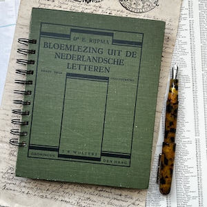 Pode incluir: Um caderno verde-oliva com espiral com o título "BLOEMLEZING UIT DE NEDERLANDSCHE LETTEREN" em texto preto. Uma caneta-tinteiro vintage com um padrão de tartaruga repousa ao lado do caderno sobre um fundo de papel envelhecido.
