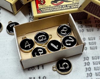 Set with 10 Enamel Charms, Flat Round, BLACK with Numbers 0~9, in vintage match box.