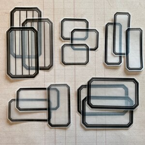 May include: A set of 10 clear, rectangular and octagonal shaped stickers with black borders. The stickers are designed to be used for labeling and organizing.
