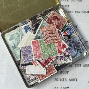 Stara puszka po papierosach z ponad 100 starymi znaczkami pocztowymi z Wielkiej Brytanii, Australii, Kanady i Nowej Zelandii. Królowa Elżbieta